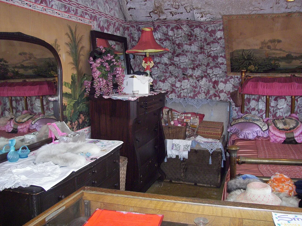 Schlafzimmer mit altem schmiedeeisernem Bett und Spiegel mit Patina
